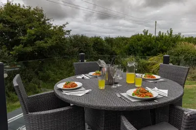 a table with plates of food and drinks on it at Teal Lodge Cornwall - hot tub, indoor pool, near Perranporth in Cubert