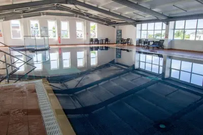 an empty swimming pool in a building at Teal Lodge Cornwall - hot tub, indoor pool, near Perranporth in Cubert