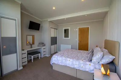 a bedroom with a bed and a desk and a television at Teal Lodge Cornwall - hot tub, indoor pool, near Perranporth in Cubert