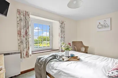 a bedroom with a bed and a window at Cherry Cottage in Saint Endellion