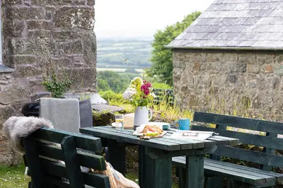 a picnic table with a plate of food and flowers on it at Cherry Cottage in Saint Endellion