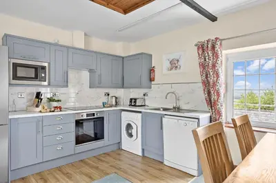 a kitchen with blue cabinets and a washer and dryer at Cherry Cottage in Saint Endellion