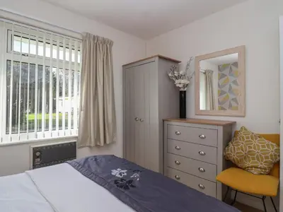 a bedroom with a bed and a dresser and a window at Westview in Liskeard