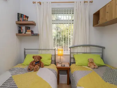 two teddy bears sitting on two beds in a bedroom at Westview in Liskeard