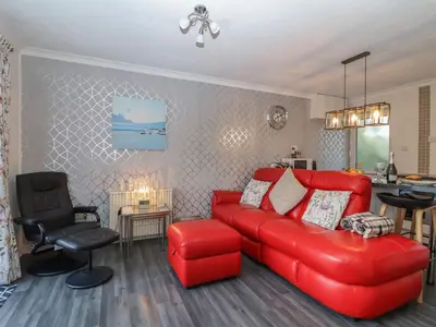 a living room with a red couch and a chair at Westview in Liskeard