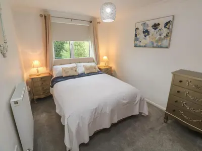 a bedroom with a white bed and a window at Sea Whispers in Marazion