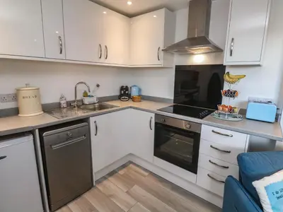 a kitchen with white cabinets and a sink at Sea Whispers in Marazion