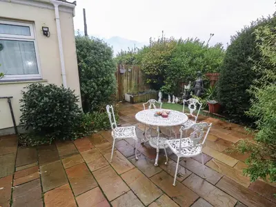 a patio with a table and chairs in a backyard at Sea Whispers in Marazion