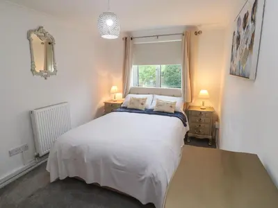 a bedroom with a white bed and a window at Sea Whispers in Marazion