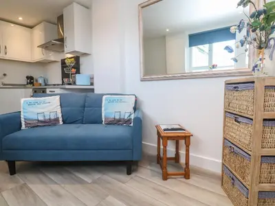 a blue couch in a living room with a table at Sea Whispers in Marazion