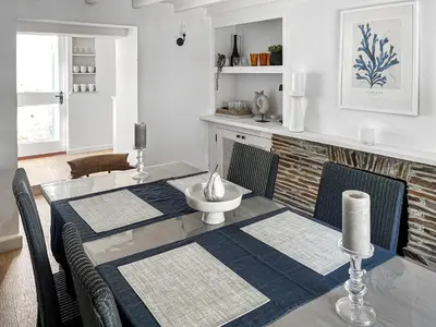 a dining room table with two chairs and a fireplace at Shearwaters in Truro