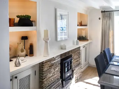 a living room with a fireplace and a table and chairs at Shearwaters in Truro