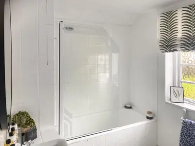 a white bathroom with a shower and a sink at Shearwaters in Truro
