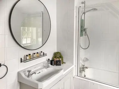 a white bathroom with a sink and a mirror at Shearwaters in Truro