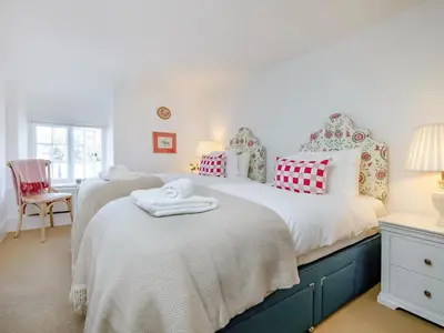 a bedroom with two twin beds and a chair at Cellars Cottage in Porthscatho