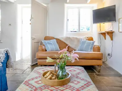 a living room with a couch and a vase of flowers at Cellars Cottage in Porthscatho