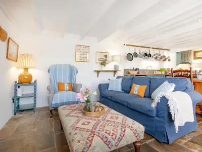 a living room with a blue couch and a chair at Cellars Cottage in Porthscatho