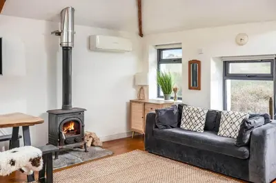 a living room with a black couch and a wood stove at Blue Skies // Porth // Newquay in Newquay