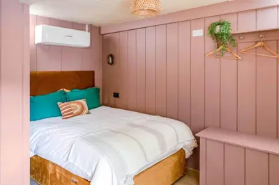 a bedroom with a bed and a pink wall at Blue Skies // Porth // Newquay in Newquay