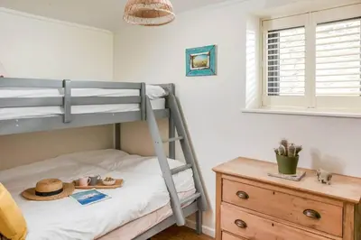 a bedroom with a bunk bed with a hat and a dresser at Blue Skies // Porth // Newquay in Newquay