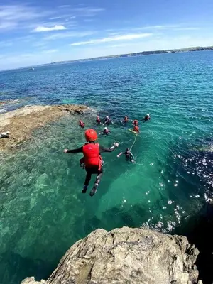 a group of people jumping into the water at Blue Skies // Porth // Newquay in Newquay