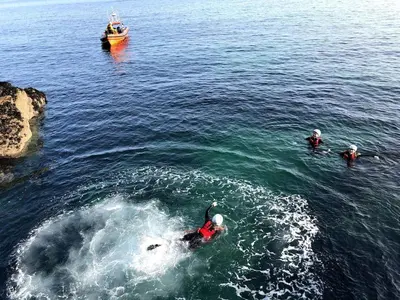 a group of people in the water with a boat at Blue Skies // Porth // Newquay in Newquay