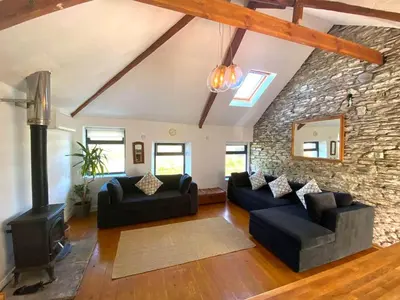 a living room with two couches and a stone wall at Blue Skies // Porth // Newquay in Newquay