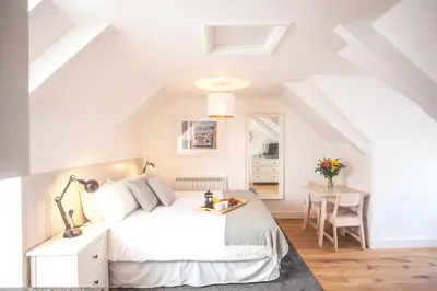 a white bedroom with a bed and a table at The Attic, Tre-Pol-Pen in St Ives