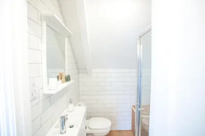 a white bathroom with a toilet and a sink at The Attic, Tre-Pol-Pen in St Ives
