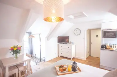 a living room with a table and a kitchen at The Attic, Tre-Pol-Pen in St Ives