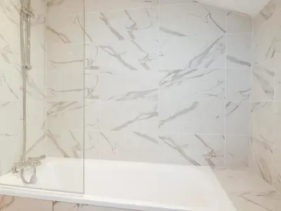 a white bathroom with a tub and marble walls at Barn 5 in St Austell