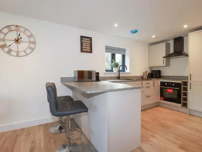 a kitchen with white cabinets and a bar with a stool at Barn 5 in St Austell