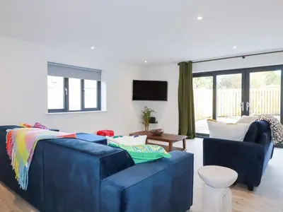 a living room with a blue couch and a tv at Barn 5 in St Austell