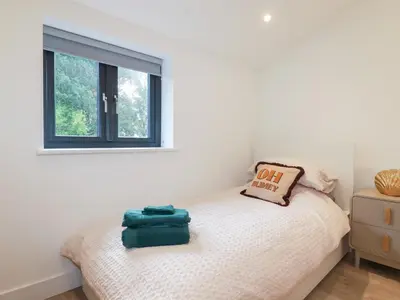 a small bedroom with a bed with a window at Barn 5 in St Austell