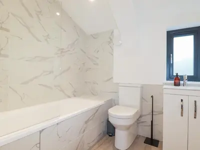 a white bathroom with a white tub and a toilet at Barn 5 in St Austell