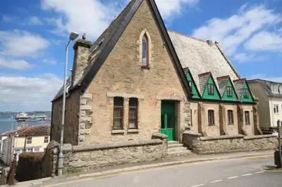 an old stone building with a green door on a street at The Quaker Hall - Private Deck - Stunning Views in Falmouth