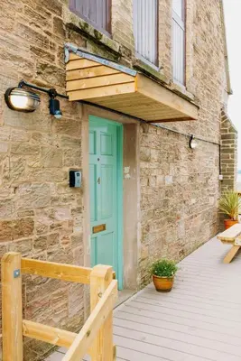 a building with a blue door and a wooden porch at The Quaker Hall - Private Deck - Stunning Views in Falmouth