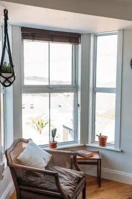 a living room with two large windows and a chair at 'Langton' - Best Views in Falmouth! in Falmouth