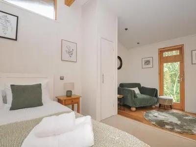 a bedroom with a bed and a chair and a window at 2 Streamside in Looe