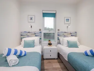 a bedroom with two twin beds and a teddy bear on a table at Adelaide in Redruth