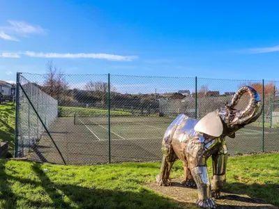 a statue of a dinosaur standing next to a tennis court at Adelaide in Redruth
