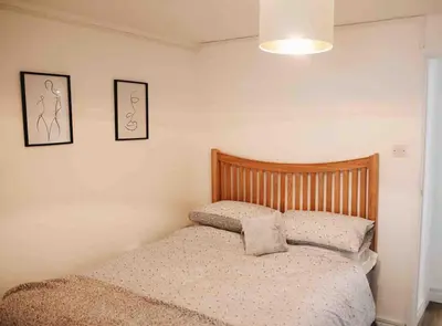 a bed in a bedroom with two pictures on the wall at Minutes from the beach and town! in Falmouth