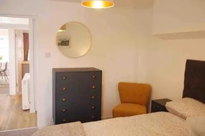 a bedroom with a dresser and a chair and a mirror at Minutes from the beach and town! in Falmouth