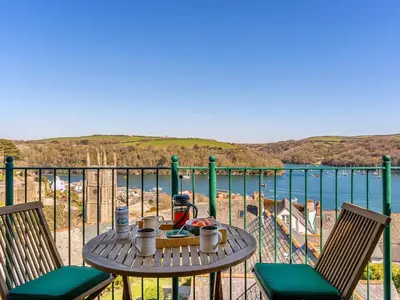 a table with a drink and two chairs on a balcony at Troy Court in Fowey