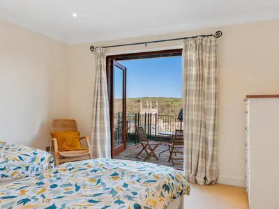 a bedroom with a bed and a sliding glass door at Troy Court in Fowey