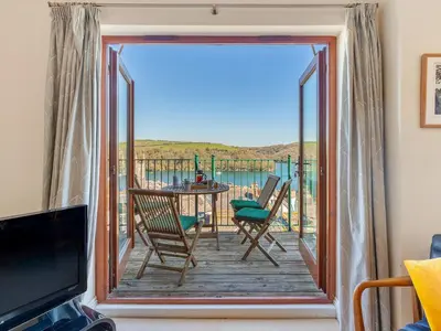 a room with a balcony with a table and chairs at Troy Court in Fowey