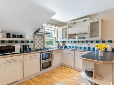 a kitchen with white cabinets and a black counter top at Troy Court in Fowey