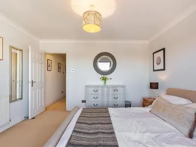 a white bedroom with a bed and a mirror at Troy Court in Fowey