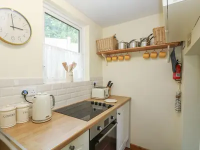 a kitchen with a counter and a clock on the wall at Driftwood Cottage in St Austell