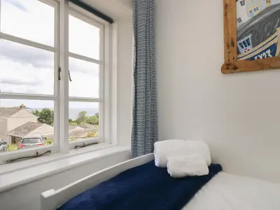 a bedroom with a bed and a window at Driftwood Cottage in St Austell